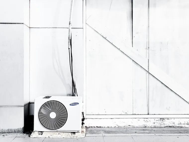 Outdoor AC condenser unit beside a Kansas City home in summer